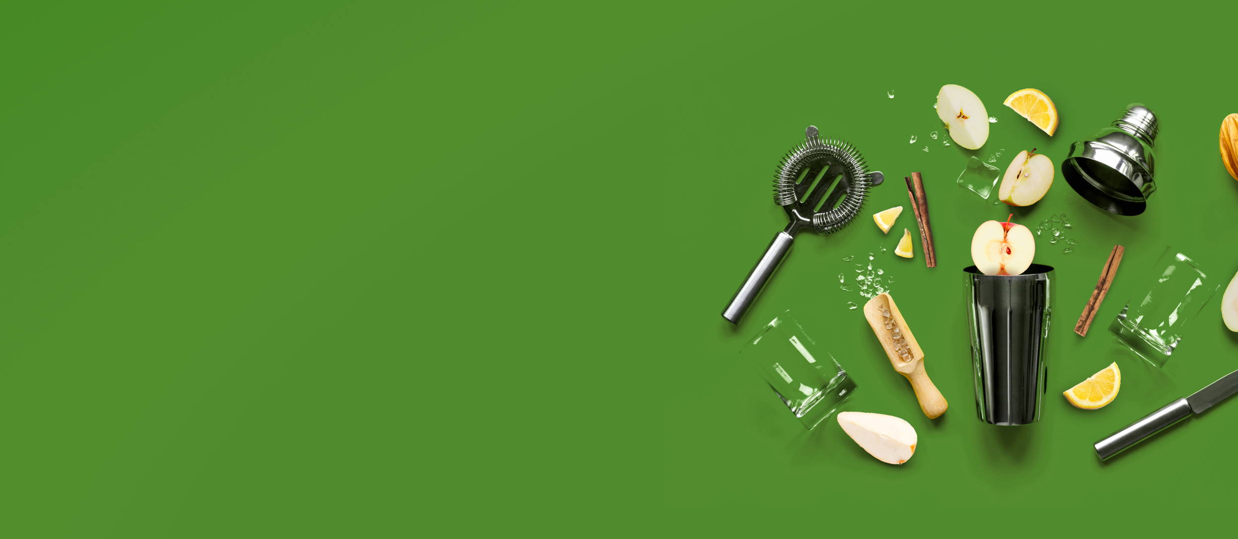 A metal shaker, strainer, ice, a glass and scoop, cinnamon sticks, and various pear and apple slices spilled out for Confetti's Virtual Online Mixology Class