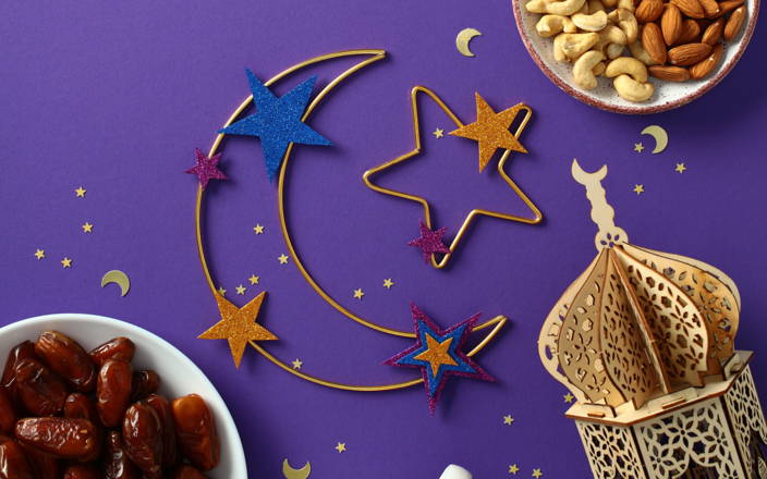 Purple background with moon and stars, small bowls of food, and a small building