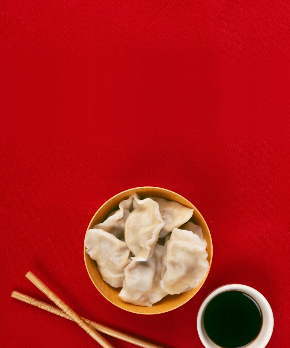 Dumplings in a bowl next to chopsticks and soy sauce for Confetti's Virtual BYO Dumpling Making Class