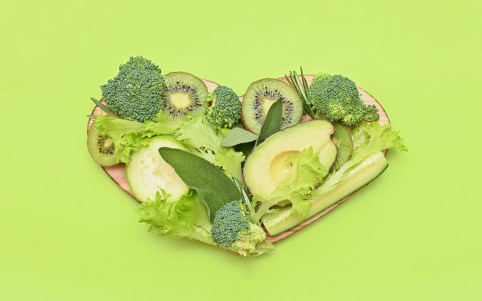 Green fruits and vegetables on a heart-shaped cutting board (preview)