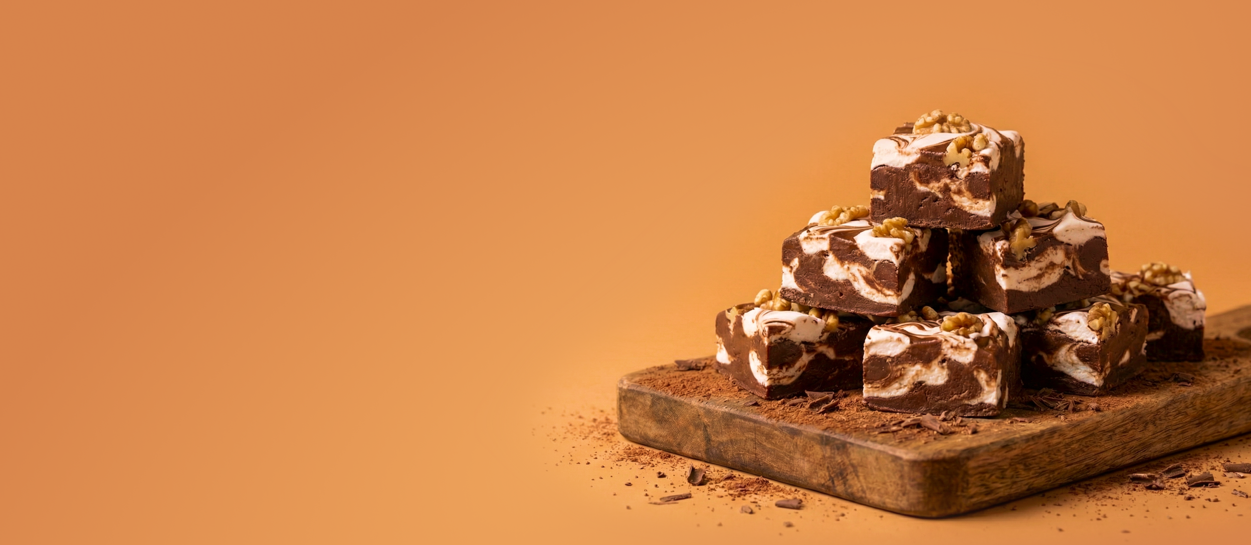 Pieces of fudge stacked on top of each other. Fudge has marshmallow swirls and walnuts.