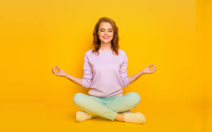 A smiling woman in a seated Sukhasana pose for Confetti's Virtual Yoga Class for Employees
