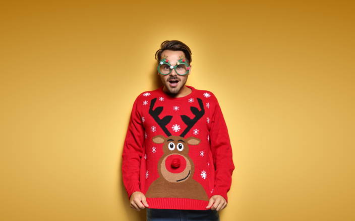 A guy wearing goofy Christmas tree glasses and a reindeer sweater for Confetti's Virtual Ugly Sweater Party