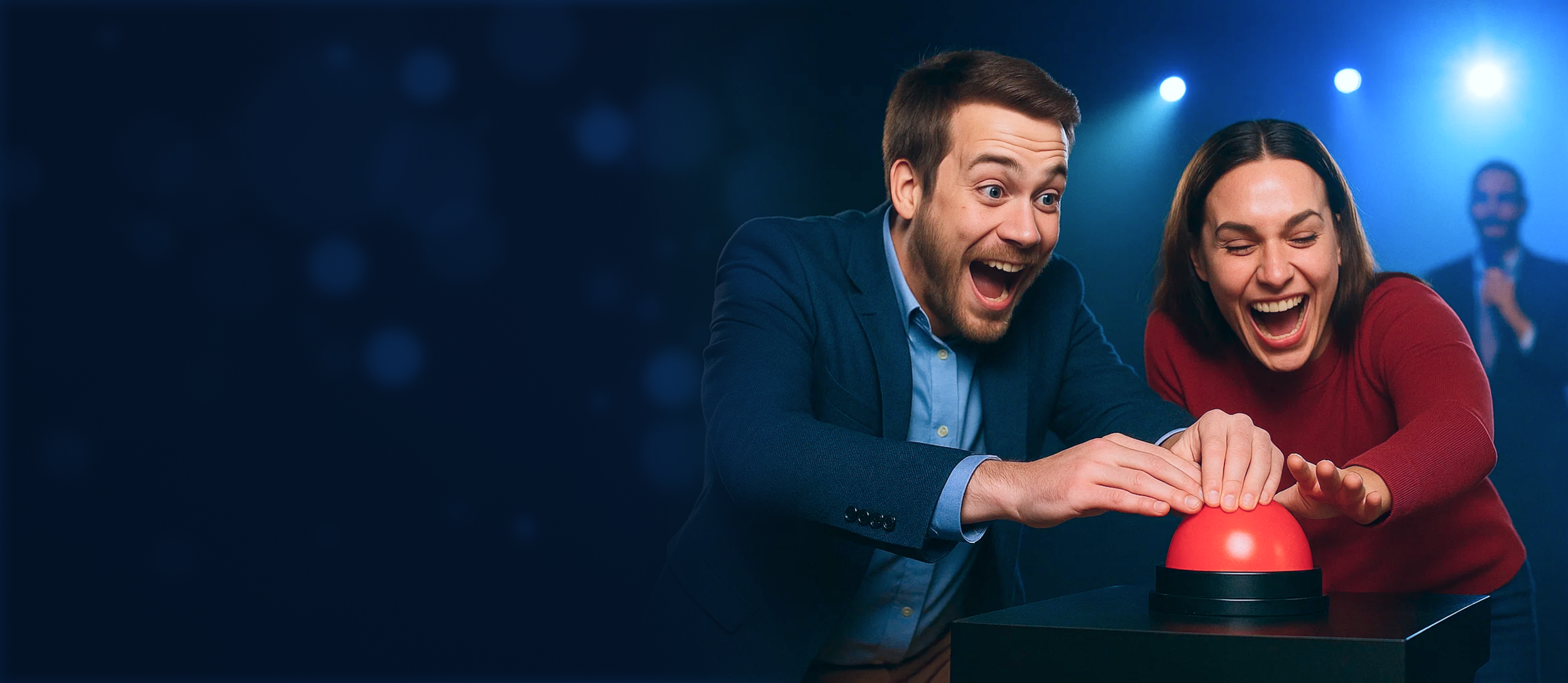 Two people, one male and one female, playing a game show. They are excited and pressing a red buzzer