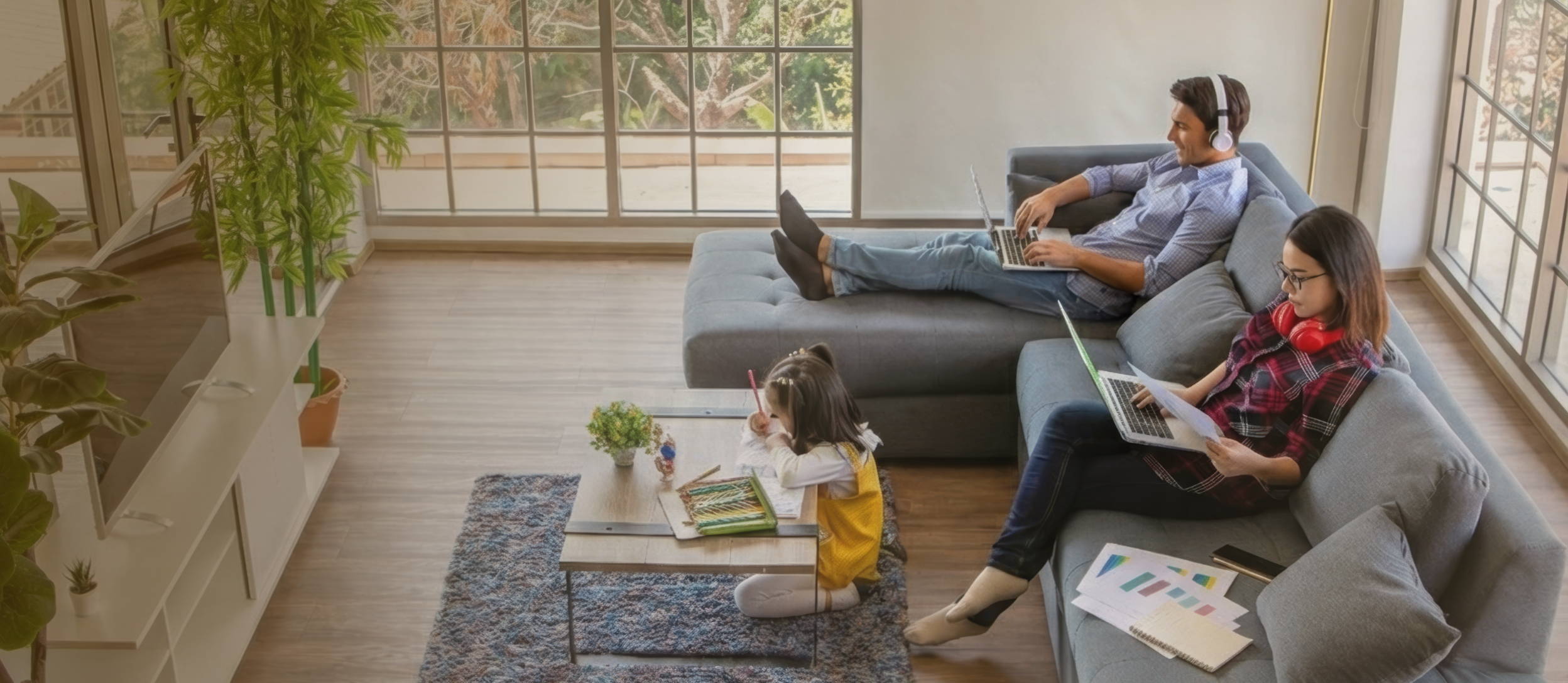 A mom & dad working from their couch in their home, while their kid colours on the floor