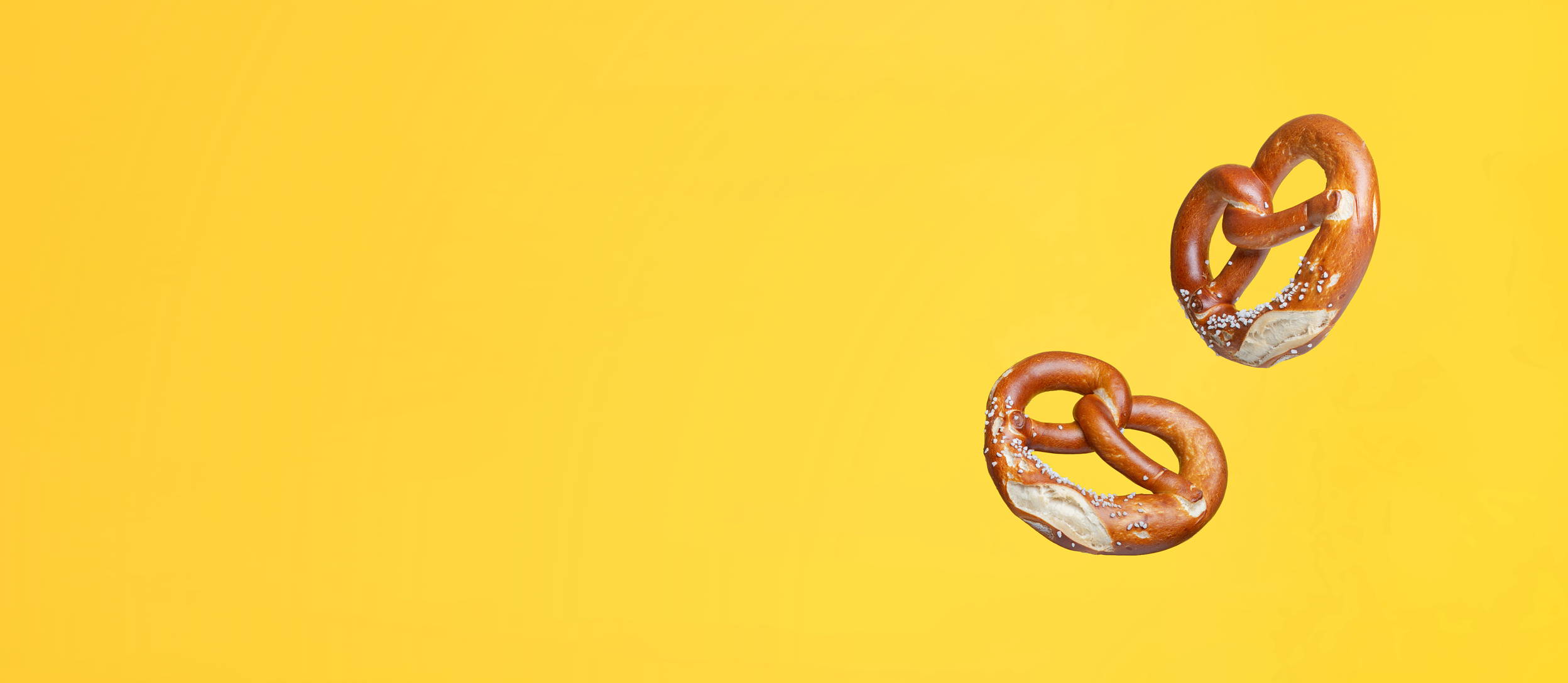 Traditional German salted pretzels floating against a yellow background (large)
