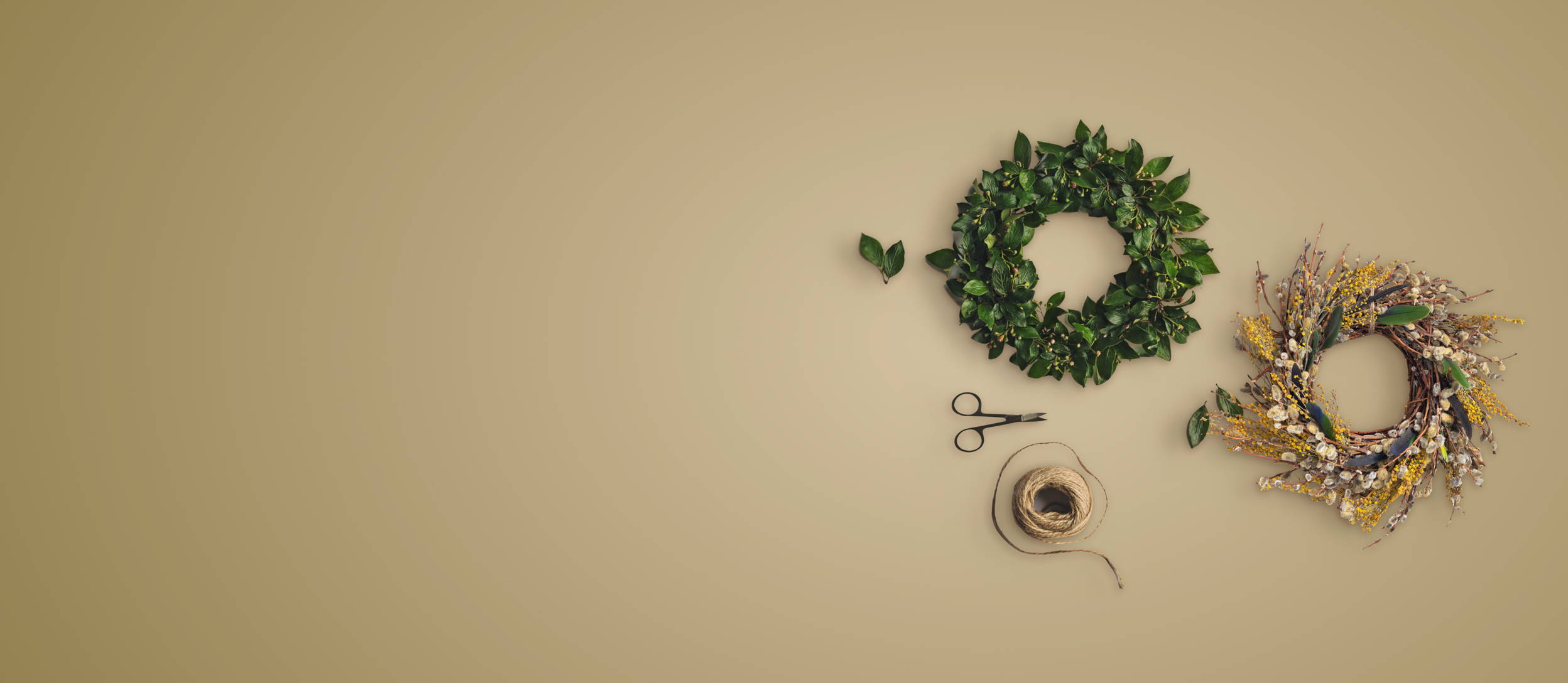 Scissors and twine next to a green wreath and a gold and tan decorative wreath for Confetti's Virtual Holiday Wreath Workshop