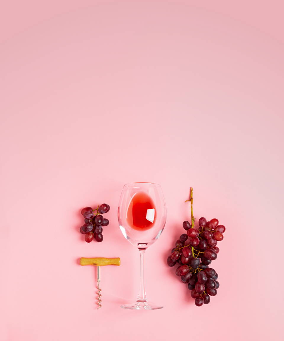 Empty glass of red wine laid flat with grapes and a corkscrew (small)