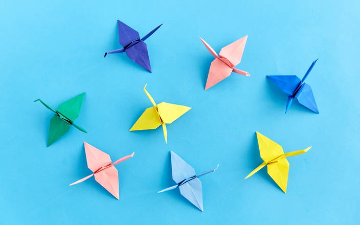 Multicolored folded origami crane designs against a blue background (preview)
