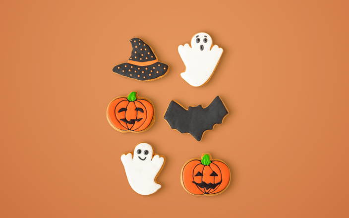Cookies shaped like a witches hat, ghosts, bats, and pumpkins for Confetti's Virtual Halloween Cookie Decorating Class