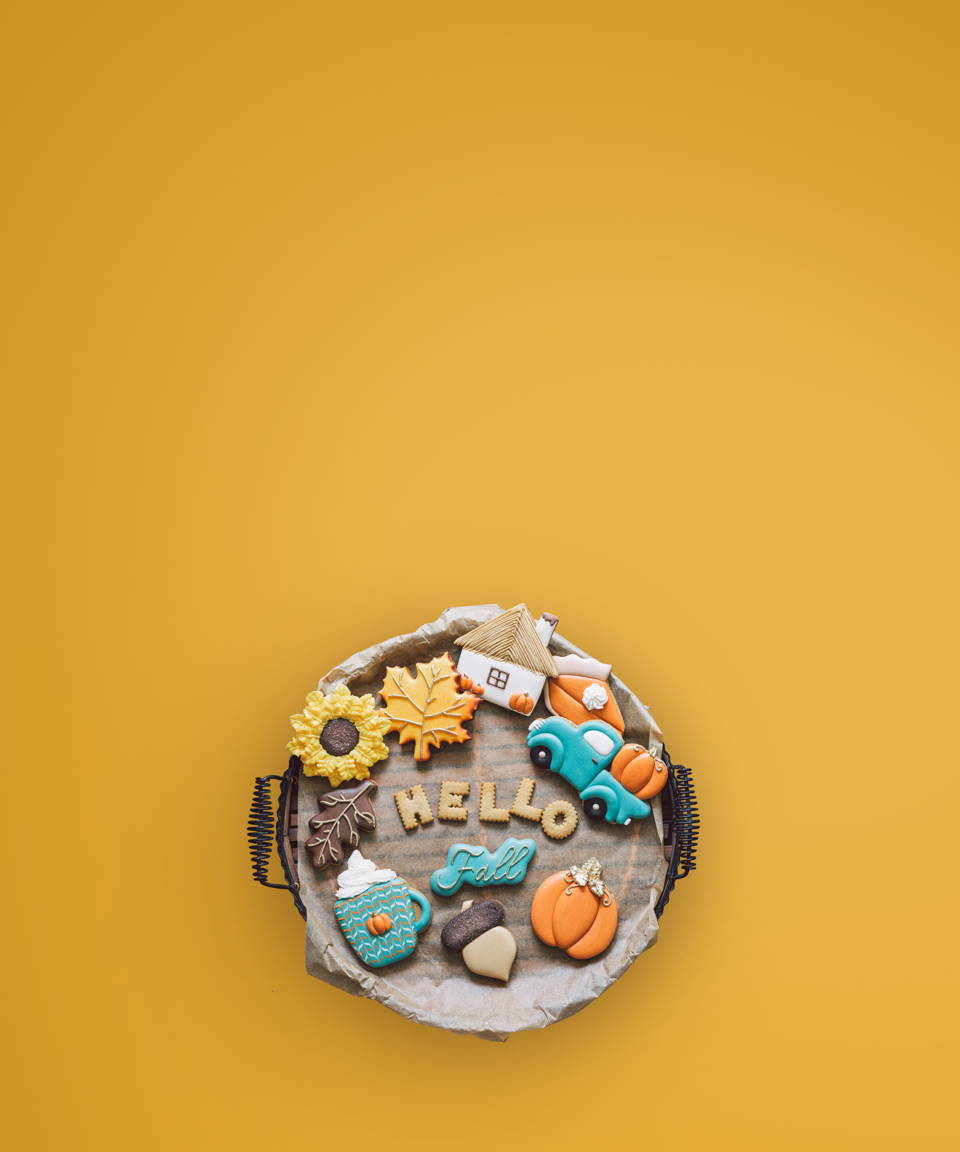 A plate of cookies iced and shaped in various autumnal shapes like pieces of pie, pumpkins, leaves, and more for Confetti's Virtual Fall Cookie Decorating