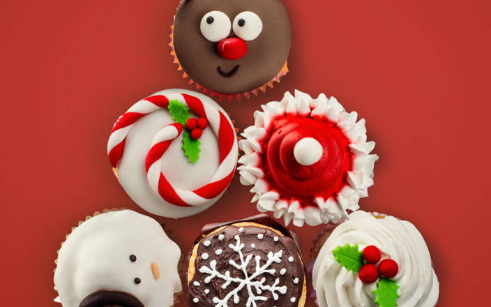 A pyramid of holiday themed cupcakes frosted in various styles for Confetti's Virtual Holiday Cupcake Decorating Class
