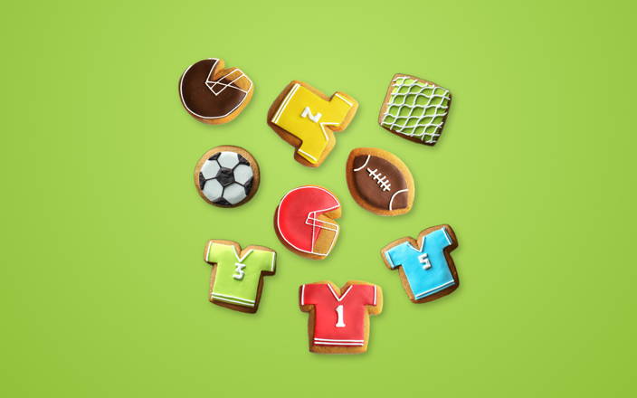 Various colorful sports theme cookies in shapes like helmets, jerseys, balls, and more for Confetti's Virtual Sports Cookie Decorating Class