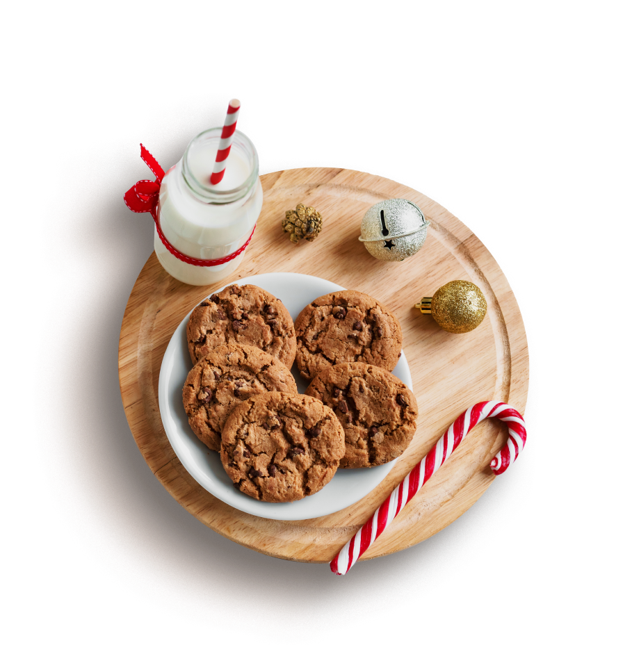 Holiday cookies placed on a tray with a glass of milk and candy cane