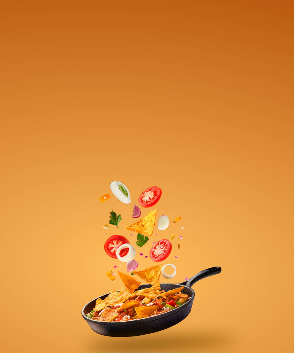 Chilaquiles cooking in a pan with vegetable garnishes floating on top (small)