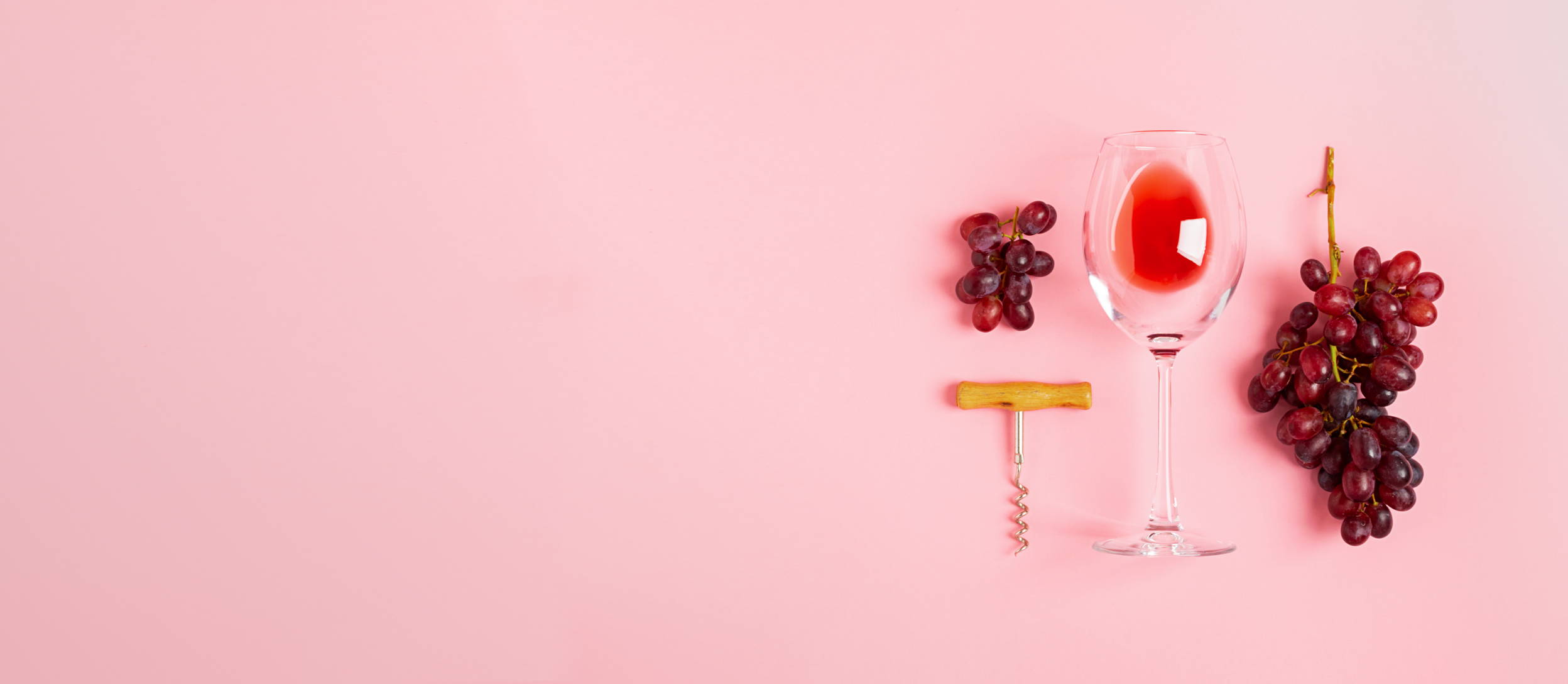 Empty glass of red wine laid flat with grapes and a corkscrew (large)