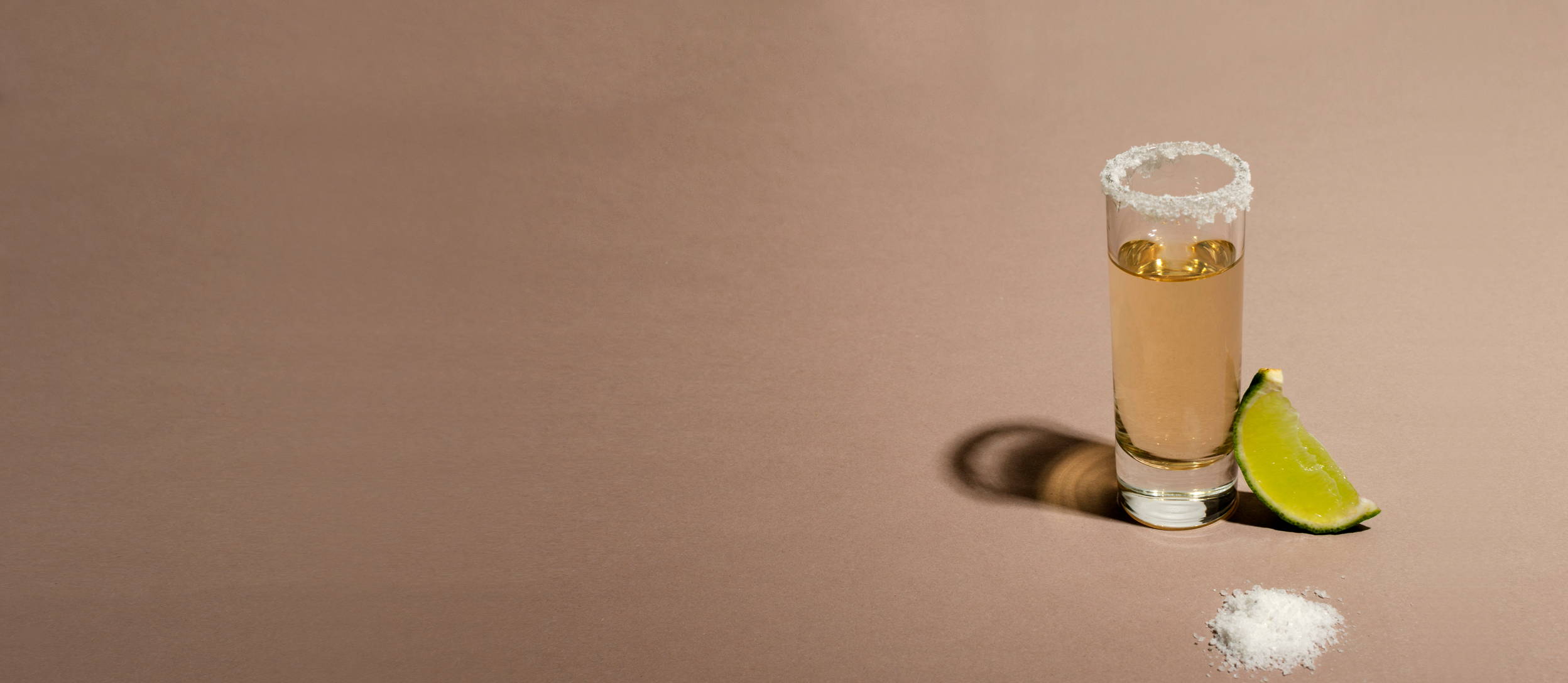 A shot of tequila with a salt rim and a lime wedge for Confetti's Virtual BYO Tequila Tasting Events