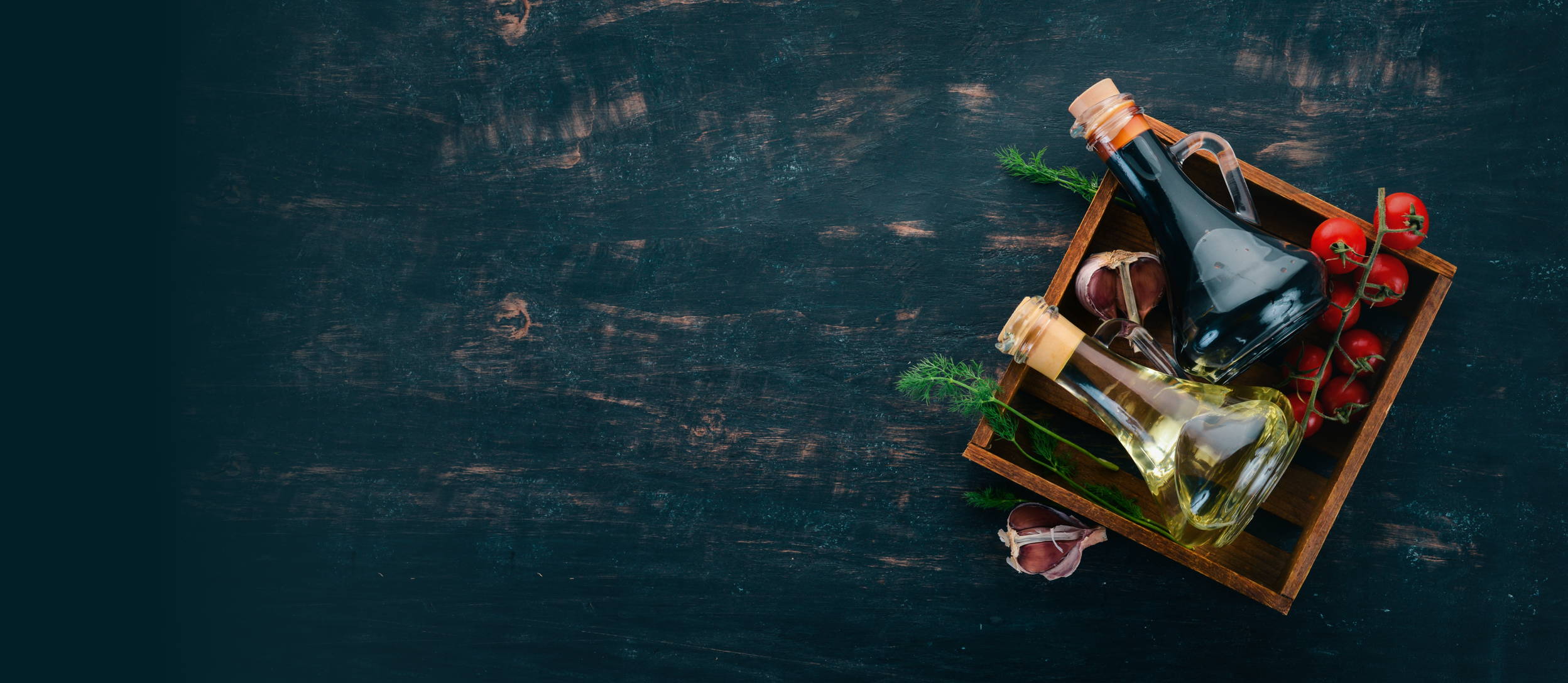 A square wooden tray with oils, vinegars, tomatoes, dill & garlic on it.