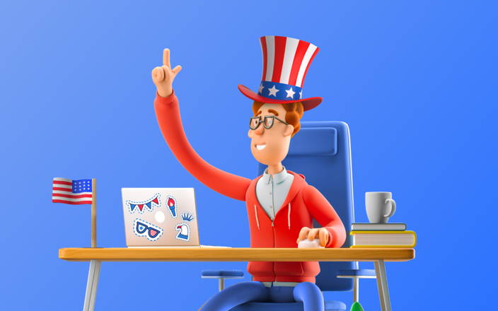 An employee sitting in front of their computer decorated in patriotic stickers, wearing a patriotic hat and hoodie, at a desk with an American Flag for Confetti's Virtual US History Trivia