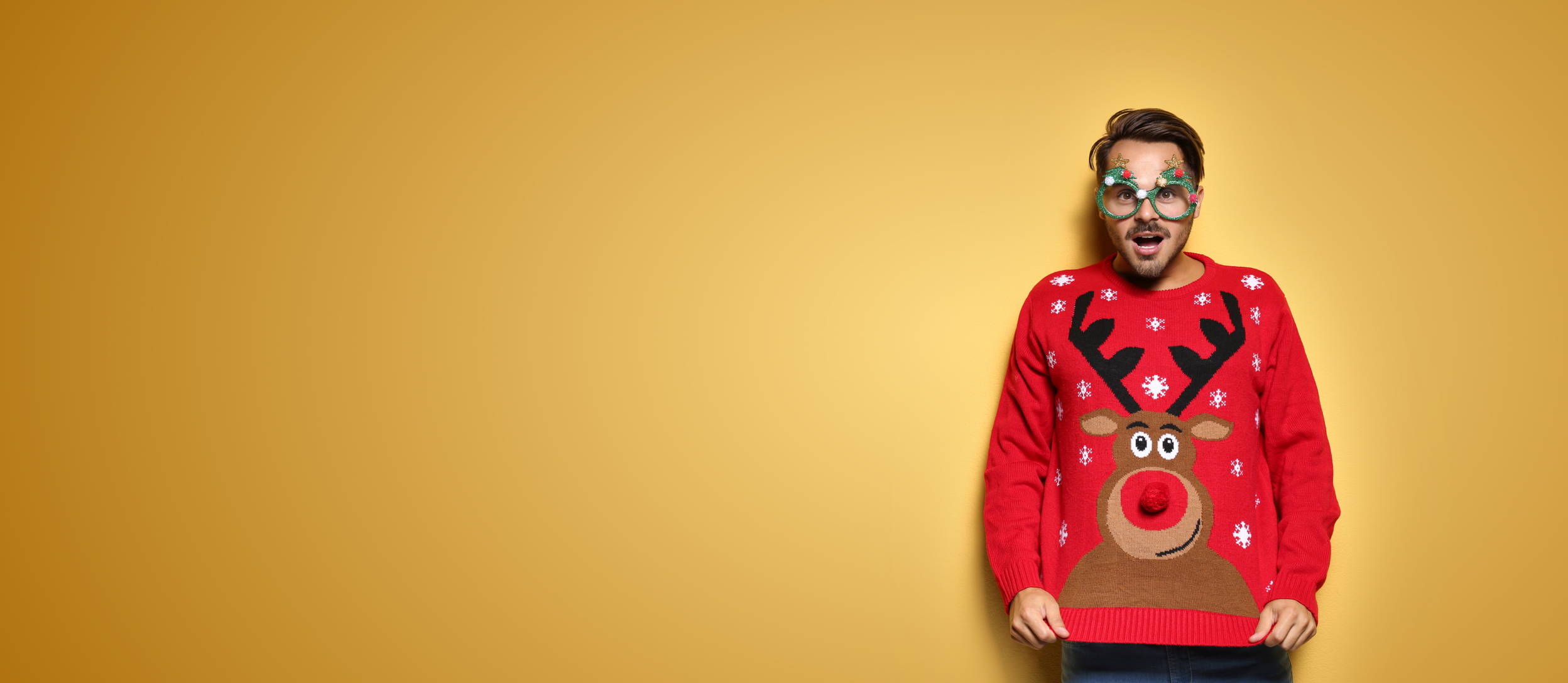 A guy wearing goofy Christmas tree glasses and a reindeer sweater for Confetti's Virtual Ugly Sweater Party