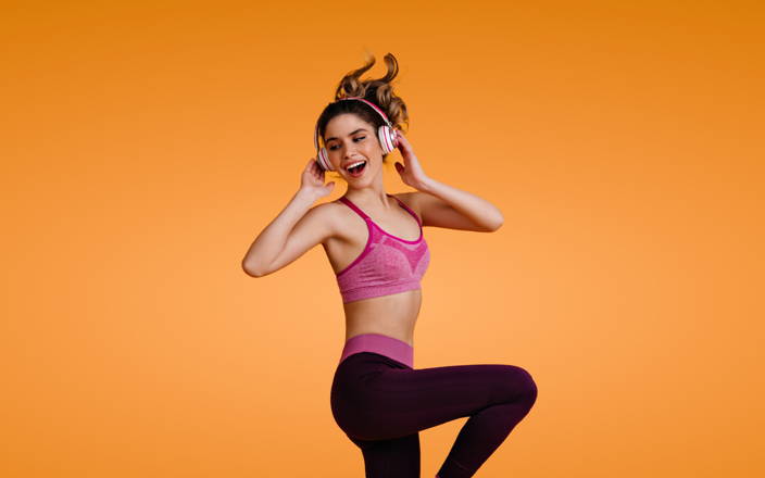 A happy girl dancing and listening to music on her headphones for Confetti's Virtual Dance Class