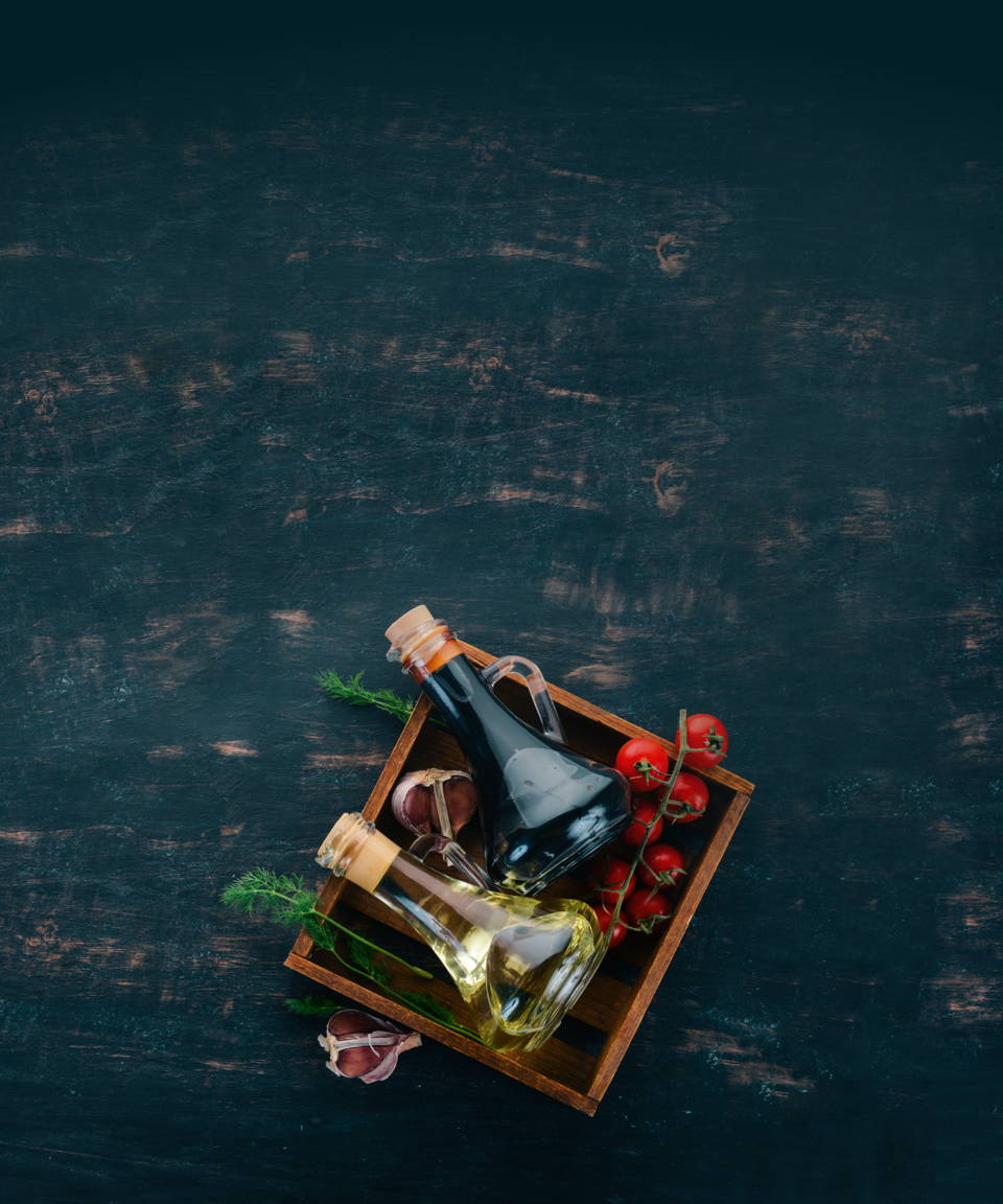 A square wooden tray with oils, vinegars, tomatoes, dill & garlic on it.