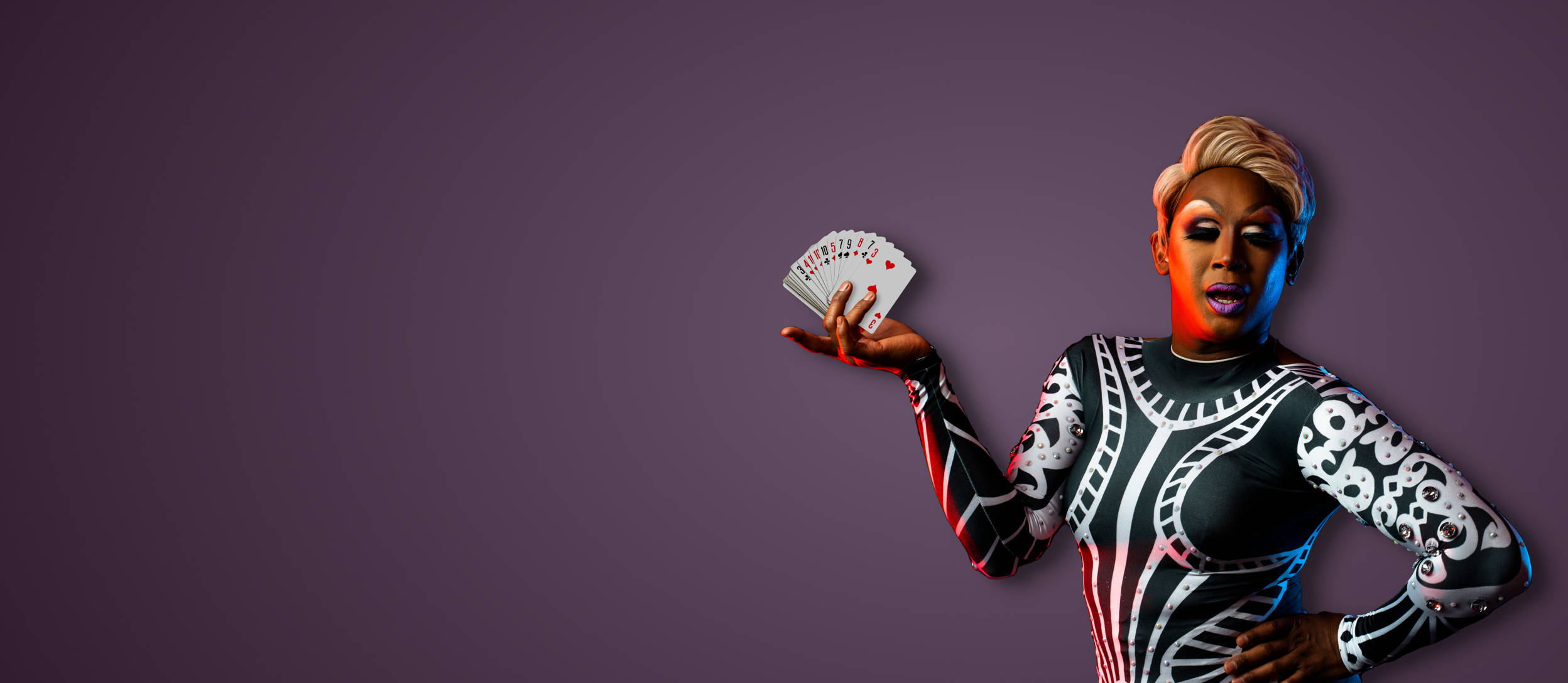 A drag queen striking a pose and holding a fanned out deck of cards for Confetti's Virtual Casino Team Building