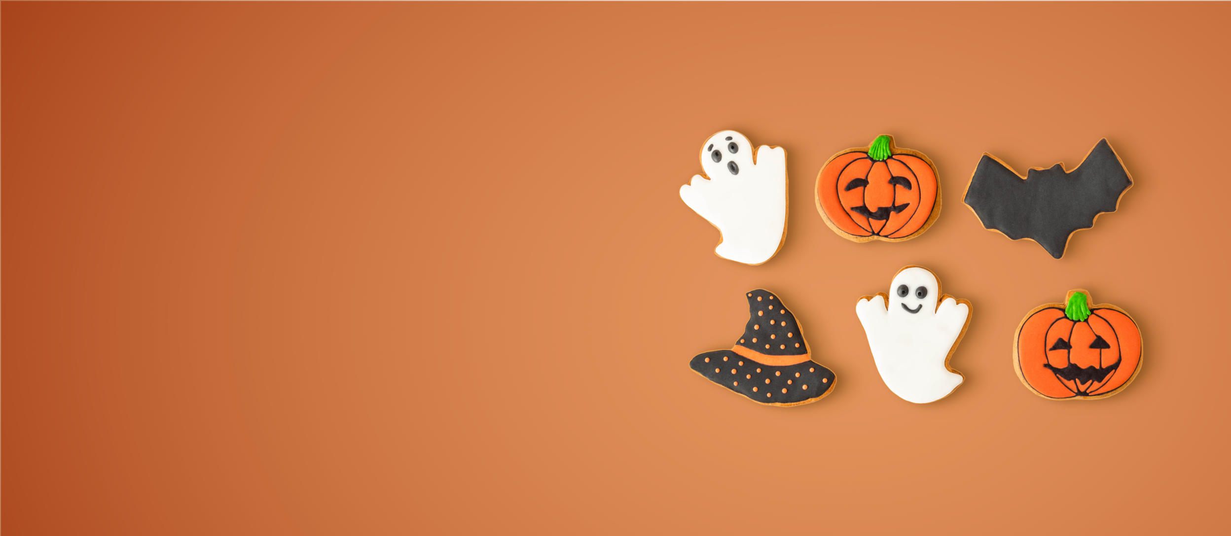 Cookies shaped like a witches hat, ghosts, bats, and pumpkins for Confetti's Virtual Halloween Cookie Decorating Class