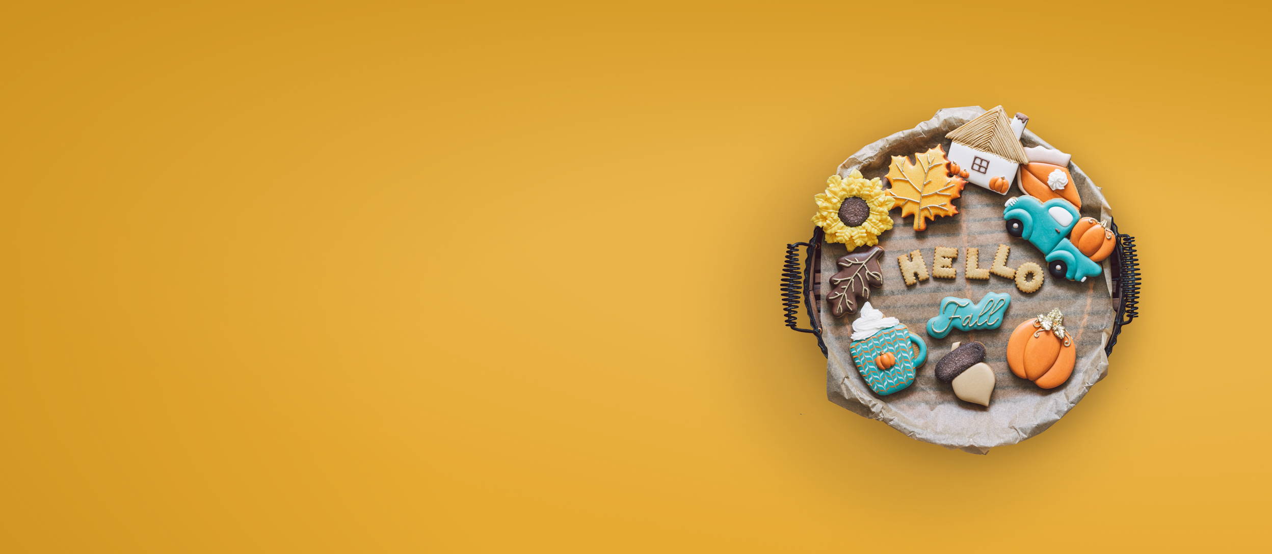 A plate of cookies iced and shaped in various autumnal shapes like pieces of pie, pumpkins, leaves, and more for Confetti's Virtual Fall Cookie Decorating Class