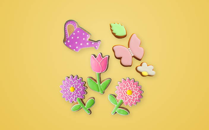 Spring cookies shaped like flowers, butterflies, and a watering pail for Confetti's Virtual Spring Cookie Decorating Class